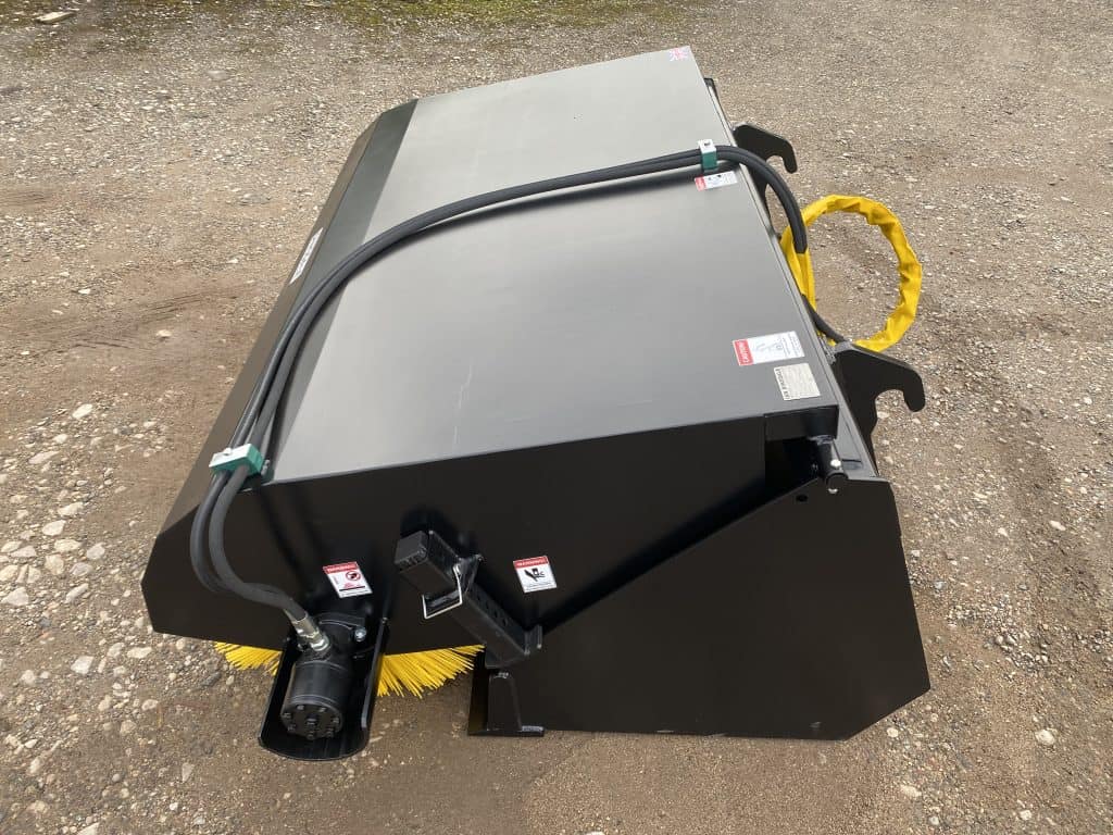 Industrial power sweeper attachment with brush for cleaning large surfaces.