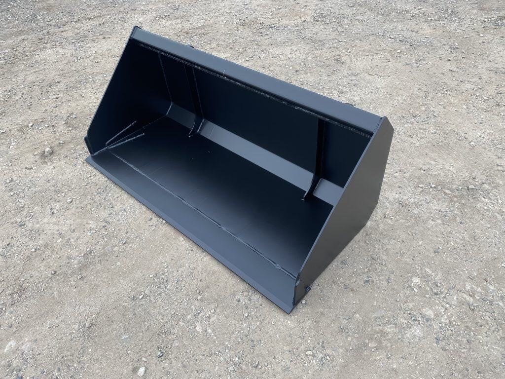 Black skid steer loader bucket on gravel surface for construction and landscaping tasks.
